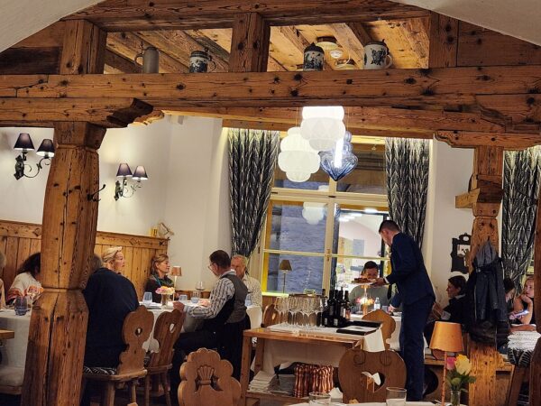 Restaurant Gasthof Goldgasse. Decorated with craftsman knotted pine wooden beams, modern lighting and large windows. There are guests enjoying fine wine, dining, and conversation.